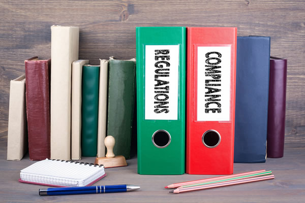 books and binders with two binders labeled regulations and compliance