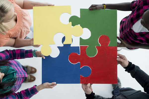 four children assembling four giant puzzle pieces