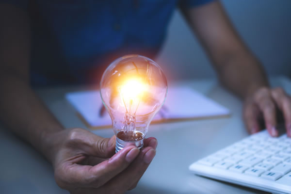 a hand holding a bright lightbulb